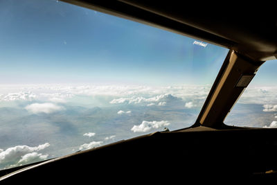 Airplane wing against sky seen through glass window