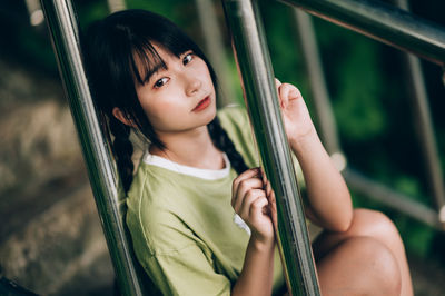 Portrait of smiling young woman standing by railing