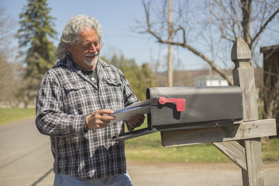 Smiling senior man removing mails from mailbox