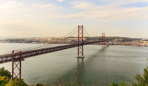 Suspension bridge over sea against cloudy sky