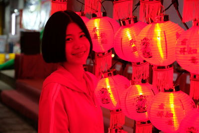 Portrait of woman standing by illuminated lanterns at night