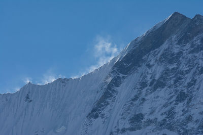 Low angle view of snowcapped mountains against sky