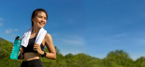 Low angle view of woman standing against blue sky