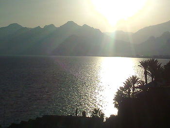 Sun shining through clouds over mountains