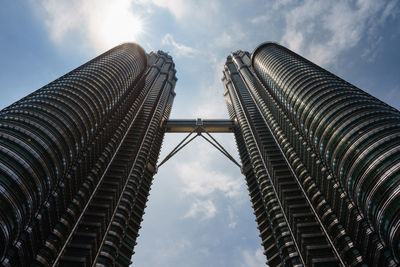 Low angle view of skyscrapers against cloudy sky
