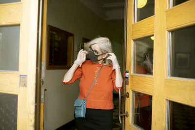 Woman putting face mask on while leaving house