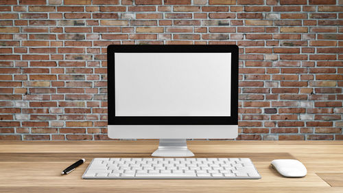 Low angle view of laptop on table against brick wall