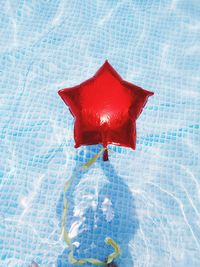 High angle view of red star shape balloon floating on swimming pool