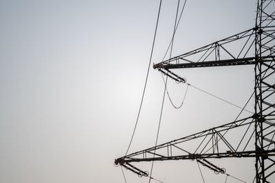 Low angle view of electricity pylon against clear sky