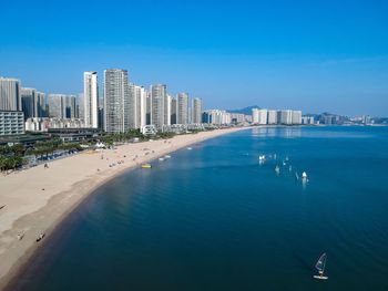 View of sea and buildings against blue sky