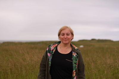 Portrait of smiling young woman standing on field