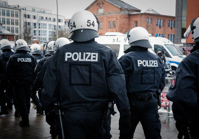 Rear view of police force walking on street in city