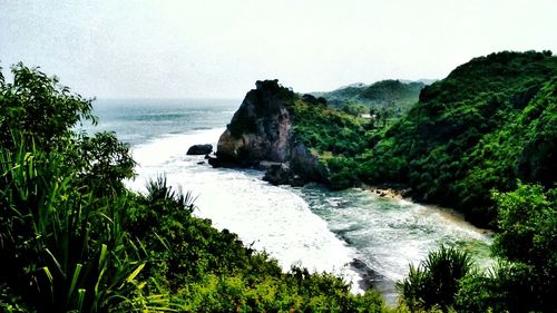 Scenic view of sea by cliff against sky