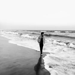 Man walking at beach against clear sky