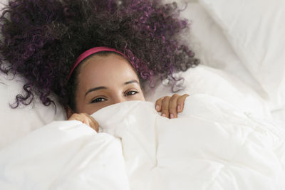 Portrait of young woman lying on bed