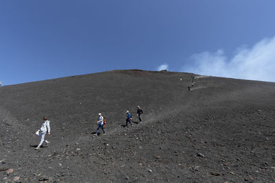 People walking on mount etna road against sky