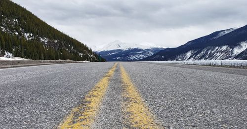 Surface level of road by snowcapped mountains against sky