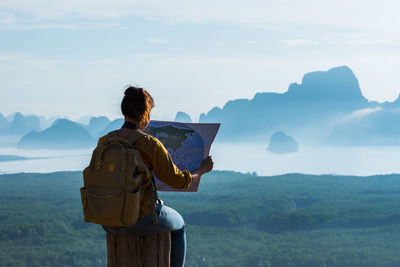 Rear view of man looking at mountains against sky