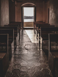 Empty pew in church with river and sky seen through window