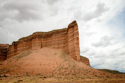 Rock formations on mountain against cloudy sky
