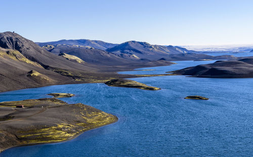 Scenic view of sea and mountains against clear sky