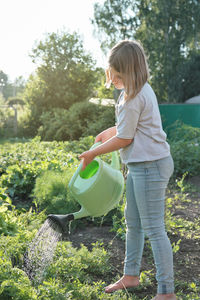 Full length of girl holding plants against trees