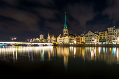 Illuminated buildings by river at night