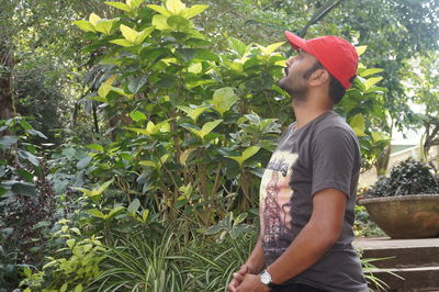 Side view of young man standing by plants