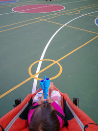 Rear view of baby girl sitting in carriage at basketball court