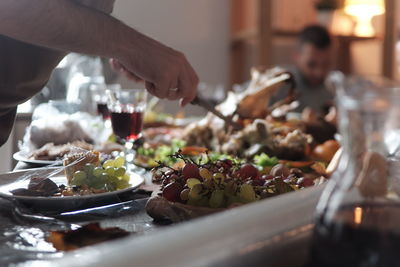 Close-up of man's hand picking up food served on table