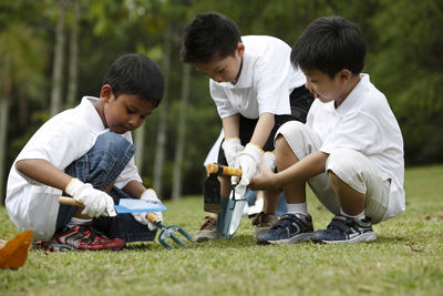 Boys playing with gardening hand tools on field