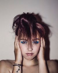 Portrait of young woman against wall