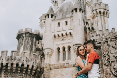 Low angle view of couple standing against historic building