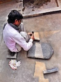 High angle view of man carving stones while sitting outdoors