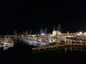 Sailboats moored in harbor at night