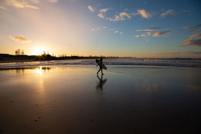 Silhouette man on beach against sky during sunset