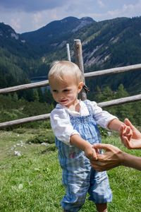 Cropped hands of mother holding daughter on mountain