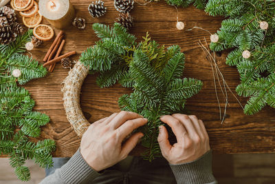 Top view of male hands making a christmas wreath from natural spruce branches