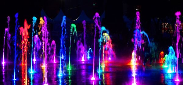 Panoramic view of colorful illuminated fountains at night