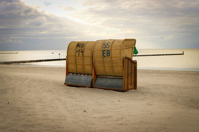 Hooded beach chair on sand against sky