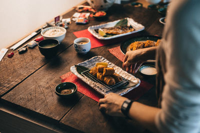 Midsection of person with food in plate on table