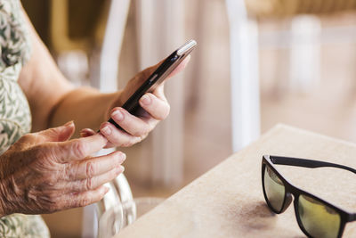 Senior woman using mobile phone while sitting by table at cafe