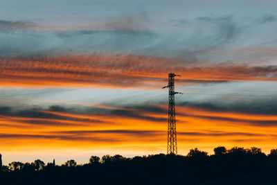 Low angle view of silhouette electricity pylon against sky during sunset