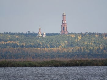 Lighthouse by buildings against sky