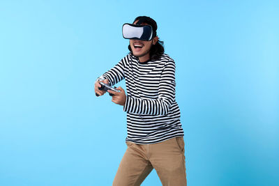 Mid adult man holding camera while standing against blue sky