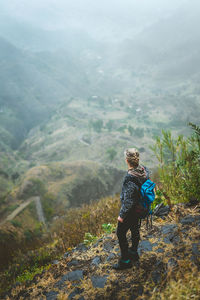 High angle view of backpacker looking at view while standing on mountain