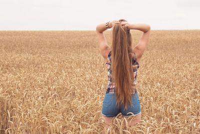 Rear view of young woman standing in farm