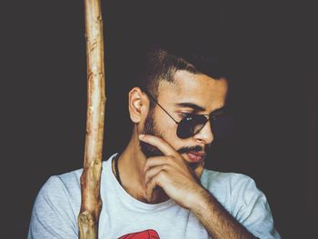 Portrait of young man looking away against black background