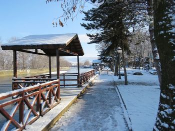 Empty benches on snow covered land against sky