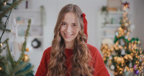 Portrait of smiling young woman standing against wall